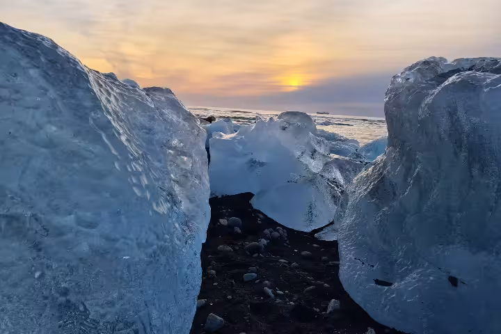 Ice chunks on Diamond Beach black sand with golden sunset over Jokulsarlon Iceland