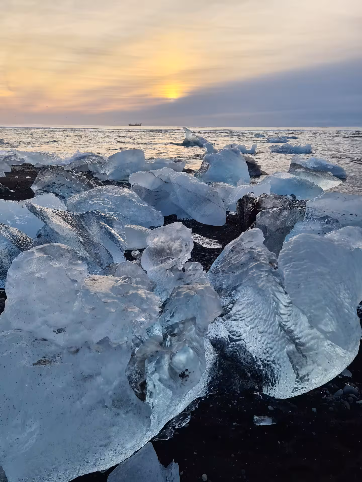 Ice chunks from Jokulsarlon glacier on Diamond Beach black sand at sunset, Iceland