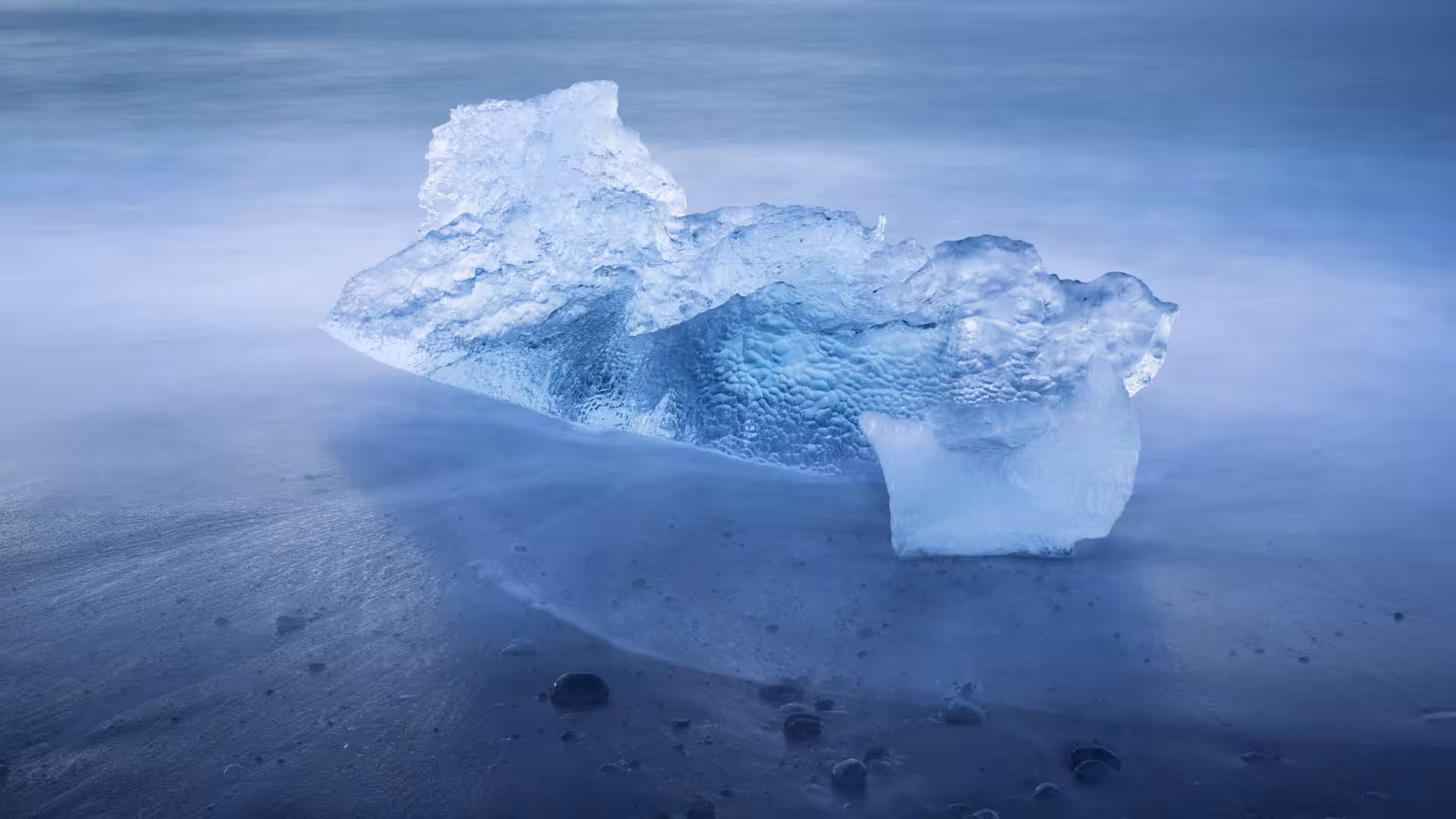 Glacial ice chunk washed ashore on Diamond Beach's black sand with misty ocean backdrop, Iceland