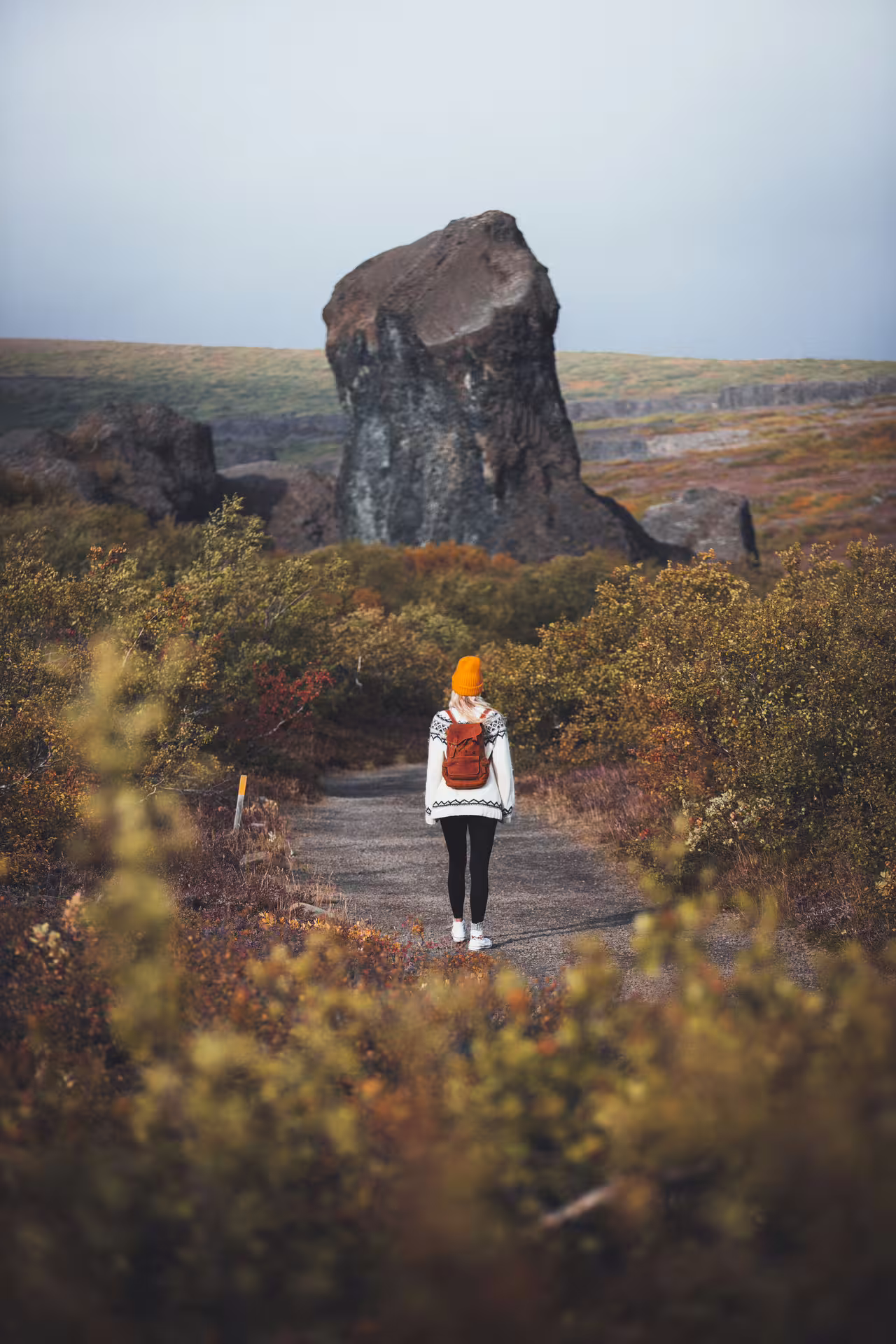 Hiker on trail toward volcanic rock formation in North Iceland's Diamond Circle landscape