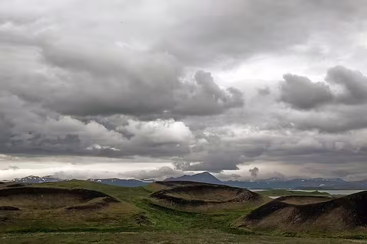 Volcanic pseudo-craters on green plains under dramatic storm clouds in North Iceland