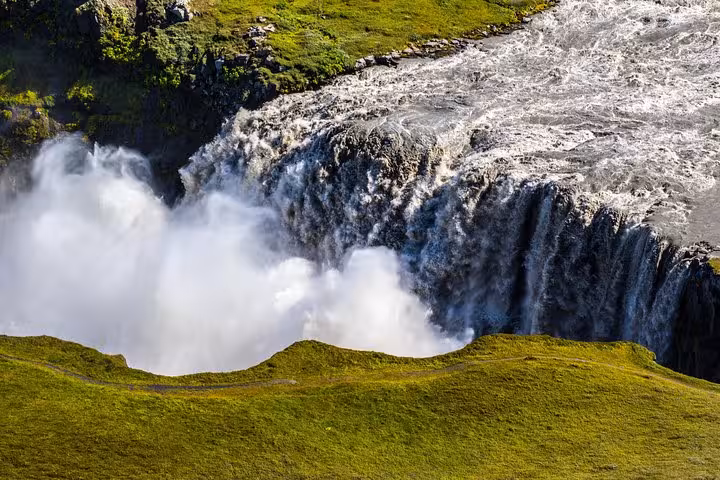Majestic waterfall cascading into a rocky abyss surrounded by lush greenery on the Diamond Circle Day Tour.