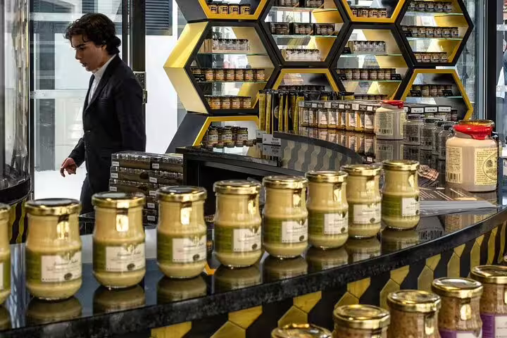 Dijon mustard jars displayed on a counter in a specialty shop with honeycomb shelving
