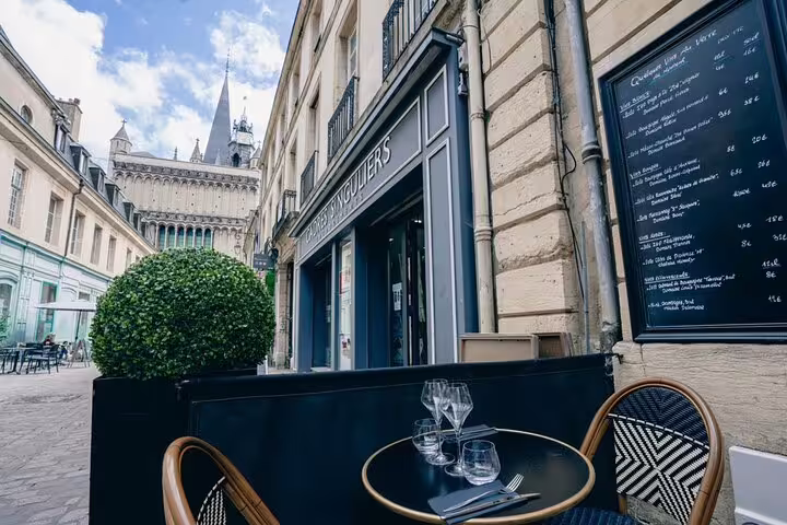 Charming French restaurant terrace with wine glasses near Gothic cathedral in Dijon city center
