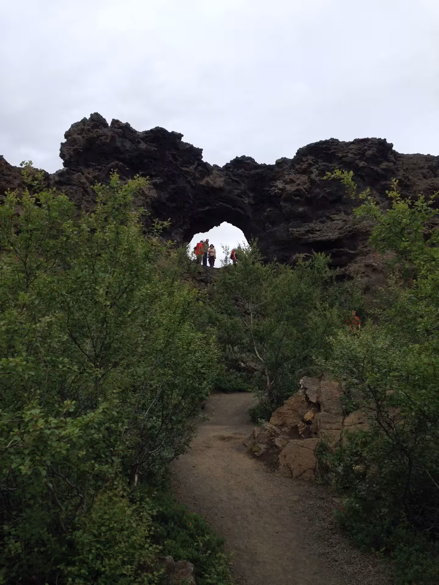 Hikers exploring Dimmuborgir lava rock arch formation on a Lake Myvatn guided day tour in Iceland