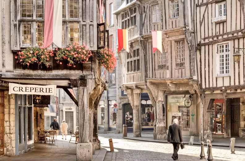 Medieval half-timbered buildings and creperie on cobblestone street in Dinan, Brittany, France