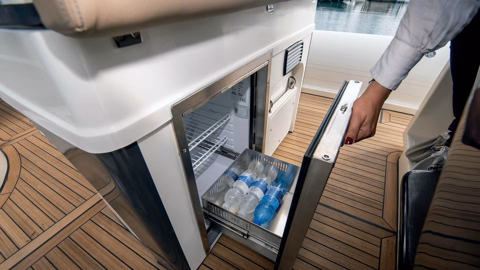 Close-up of an open fridge on a dinghy stocked with bottled water, perfect for a La Maddalena beach tour refreshment.