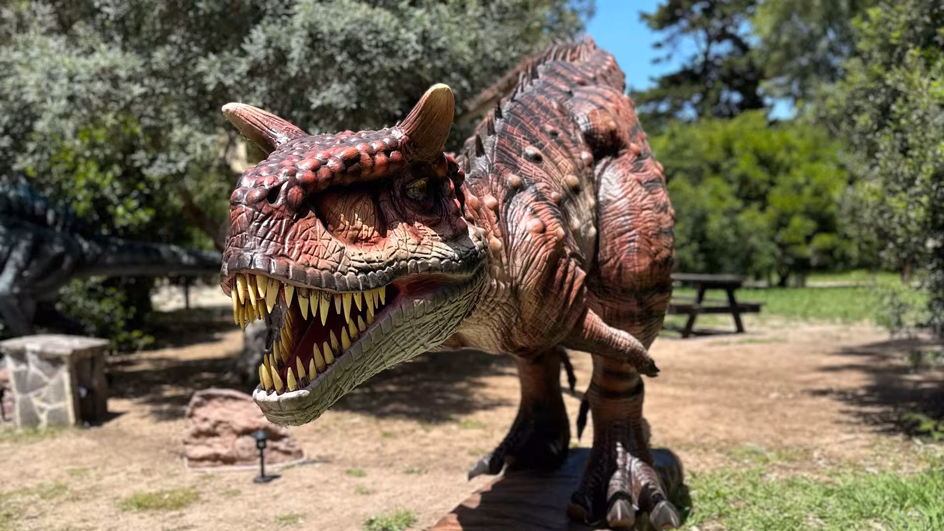 Lifelike dinosaur sculpture in Porto Conte Park, Alghero, surrounded by lush greenery, ideal for dinosaur enthusiasts.