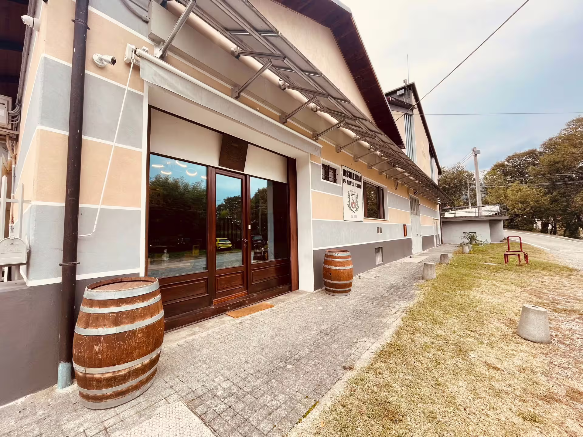 Side angle of a distillery entrance near Turin, showcasing wooden barrels and rustic architecture.