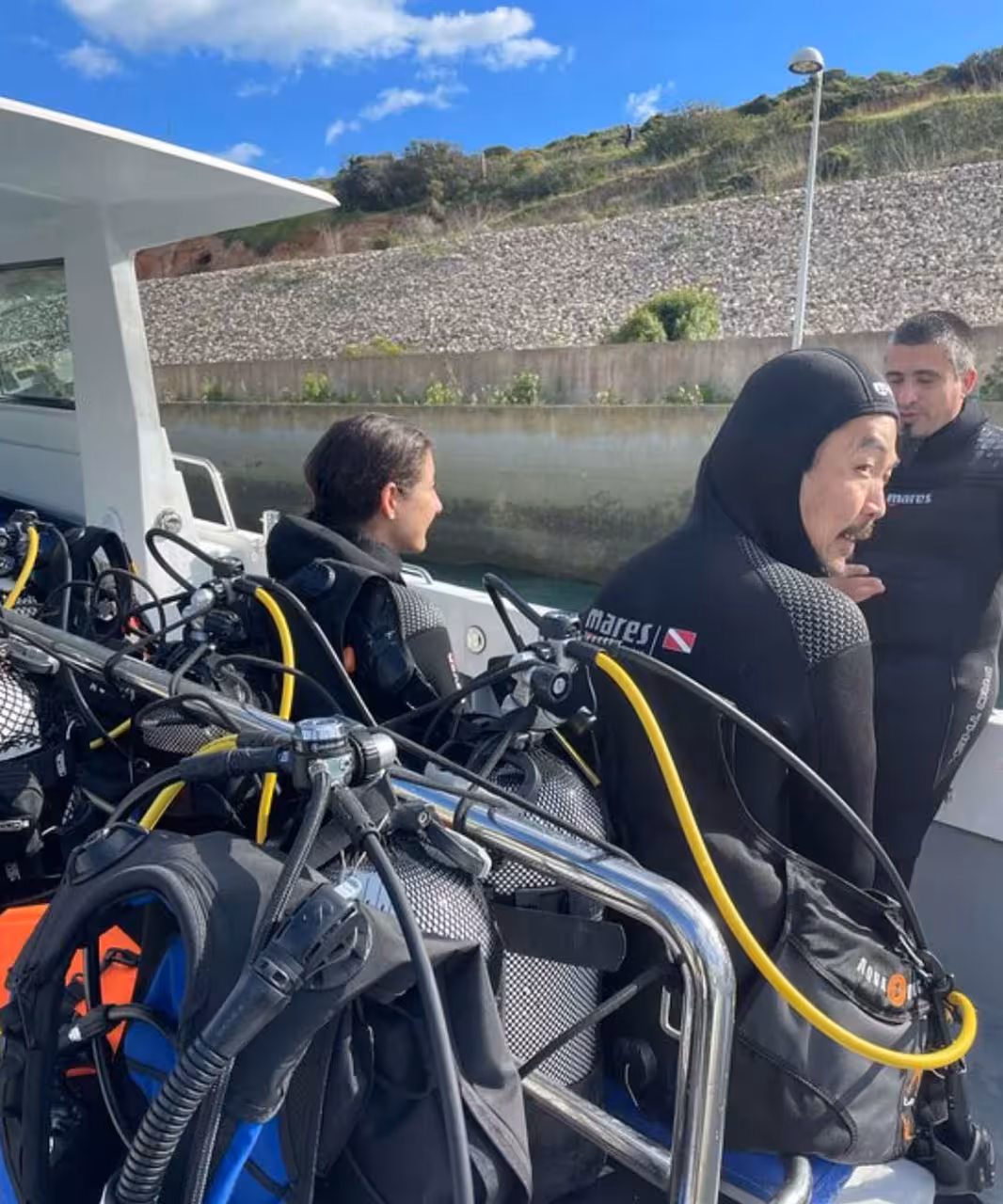 Divers in wetsuits with full scuba equipment on boat, preparing for try dive diving baptism with instructor