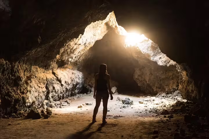 Traveler inside Djara Cave with sunbeam at entrance, highlight of Egypt White Desert 5-day adventure tour
