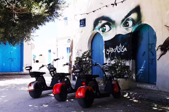 Three E-Scooter Harleys parked near striking street art in Djerbahood, ideal for exploring cultural murals on tour.
