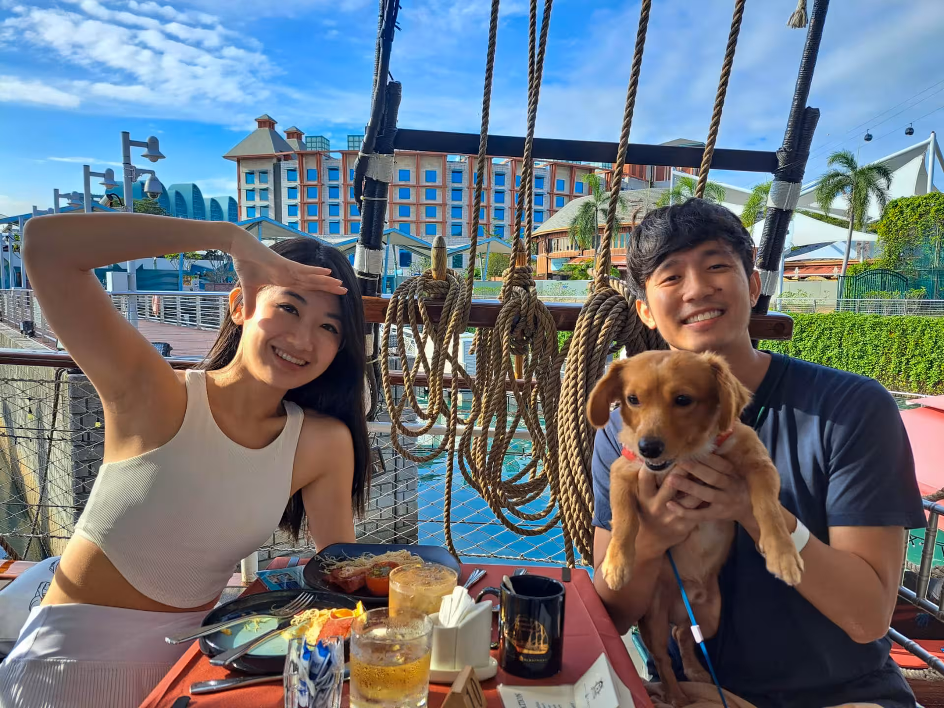 Couple and their dog enjoying a sunny day on a Royal Albatross cruise with a view of waterfront and seated dinner.