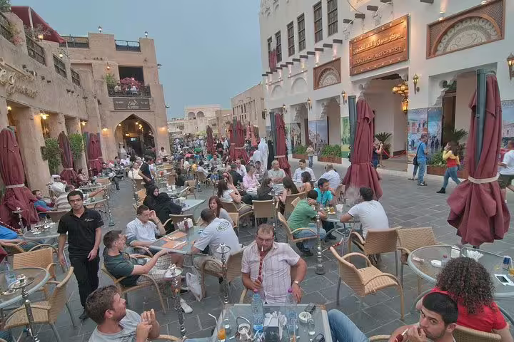 Visitors enjoying outdoor dining and vibrant atmosphere at Souq Waqif, a key stop in Doha's customizable city tour.