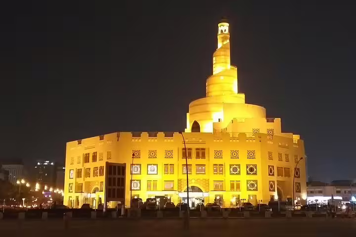 The iconic spiral mosque in Doha glowing at night, essential stop on the Doha city tour and dhow boat ride.