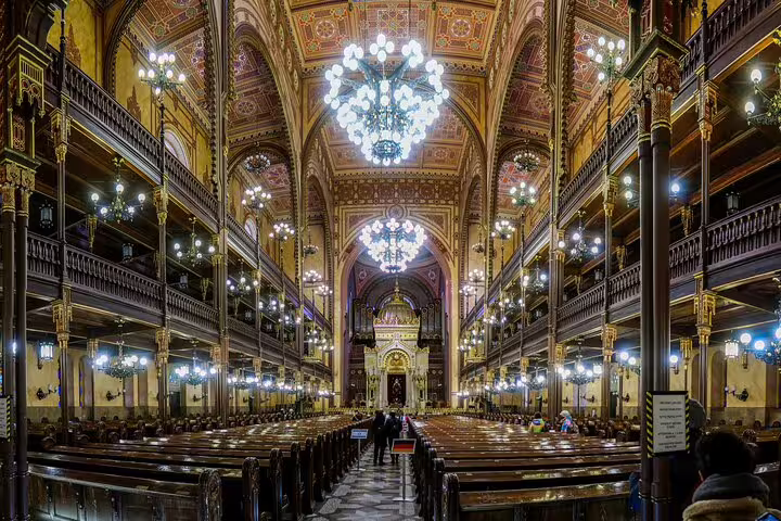 Grand Dohány Street Synagogue nave with chandeliers and wooden pews, Budapest Jewish District tour