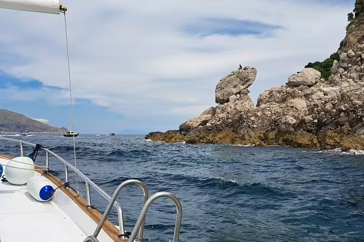 Classic boat cruising past rocky Capri coastline on a 4-hour private tour, with open sea views