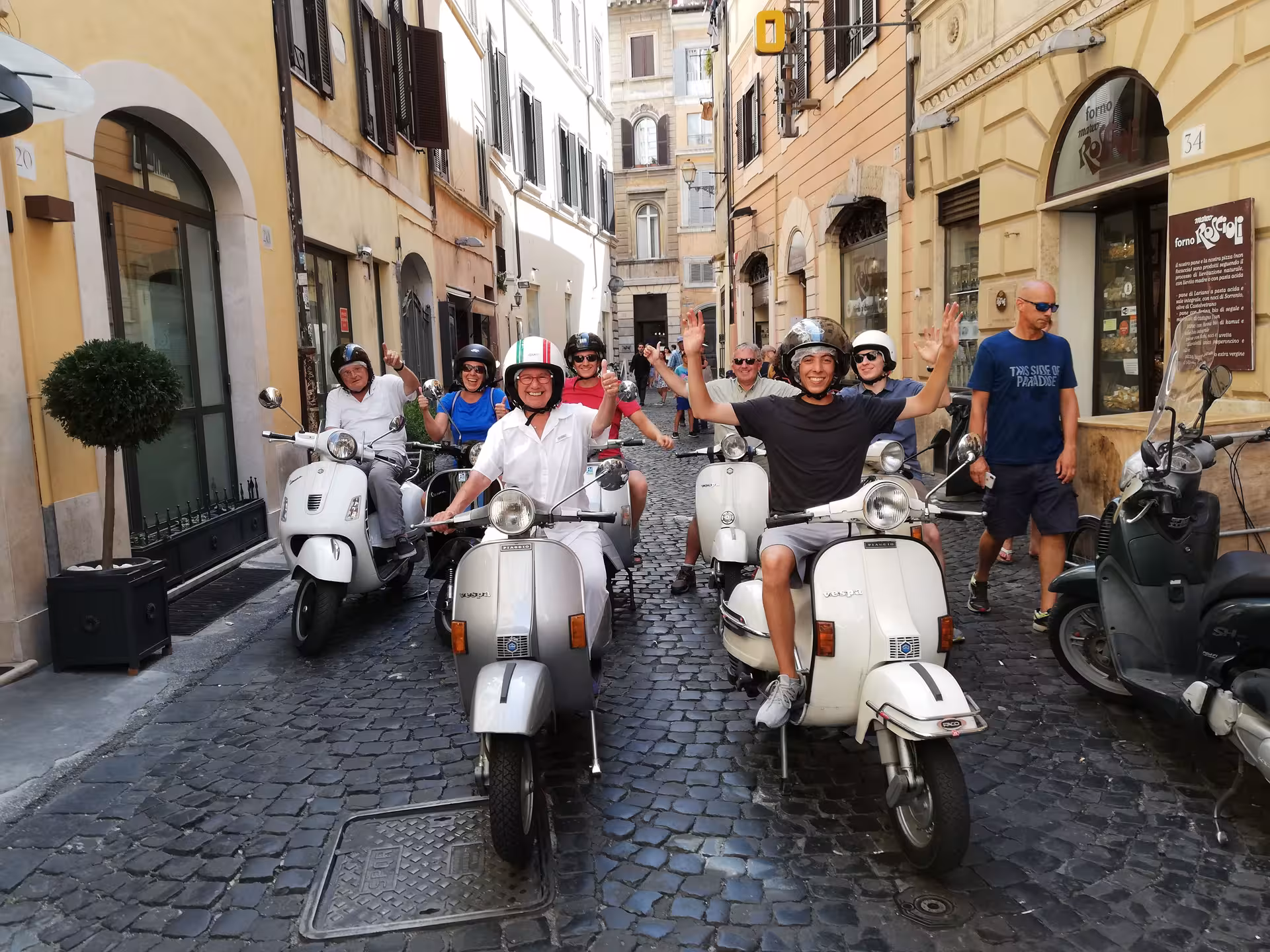 Group of happy riders on Vespas exploring Rome's charming streets on the Dolce Vita Vespa Tour.