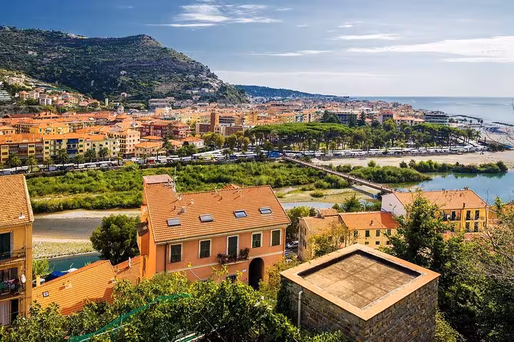 Panoramic view of colorful Italian coastal town with terracotta rooftops, river, and Mediterranean sea backdrop