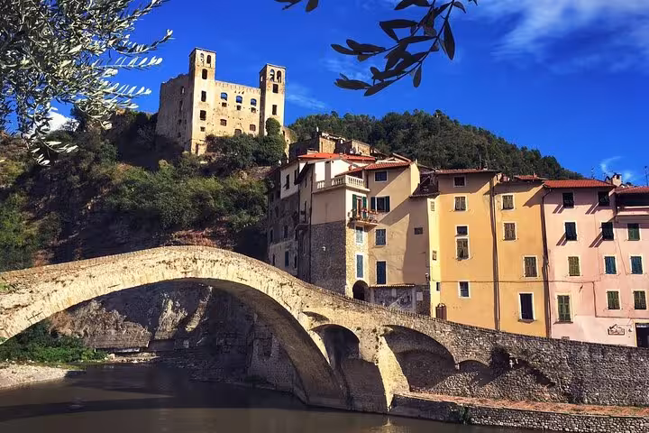Medieval stone arch bridge over river with colorful buildings and castle ruins in Dolceacqua, Italy