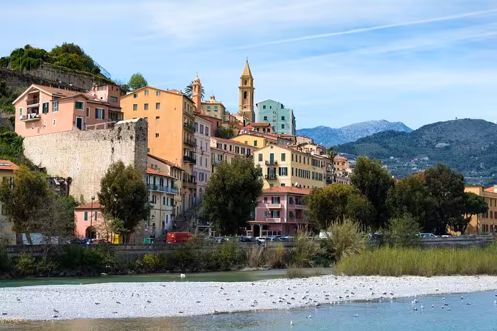 Colorful historic buildings of Dolceacqua village along a river with mountains in background, Italian Riviera