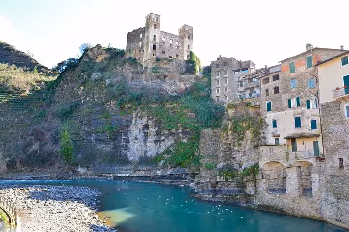 Medieval castle ruins on cliffs above turquoise river in Dolceaqua, Italian Riviera village