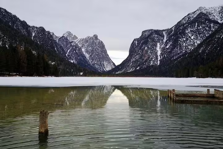 Tranquil frozen lake surrounded by snow-capped mountains in the Dolomites, perfect for a serene day trip from Venice.