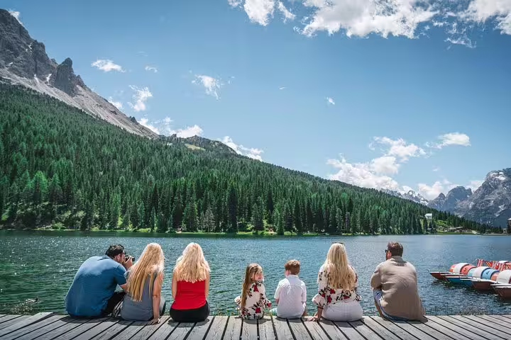 Family relaxing by a serene Dolomite lake, experiencing nature's beauty on a private Venice day tour.