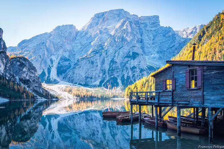 Picturesque mountain lake with wooden boathouse reflecting the Dolomites, featured on a day trip from Venice.