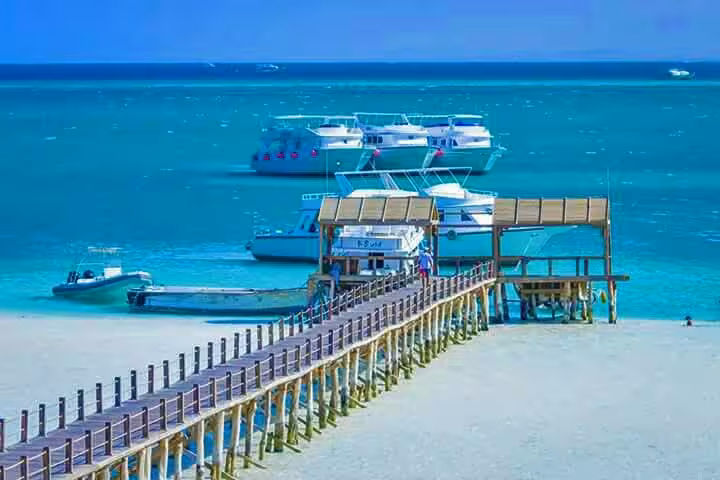 Long pier to boats in turquoise Red Sea, departure point for Dolphin House National Park snorkeling trip
