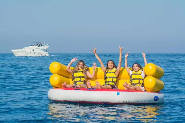 Guests in life jackets waving on banana boat in Red Sea, Dolphin House snorkeling VIP boat from Hurghada