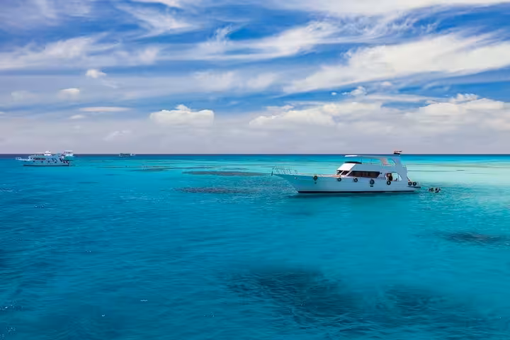 Boat anchored in turquoise Red Sea at Dolphin House Samadai Reef, Marsa Alam, for a guided snorkeling adventure