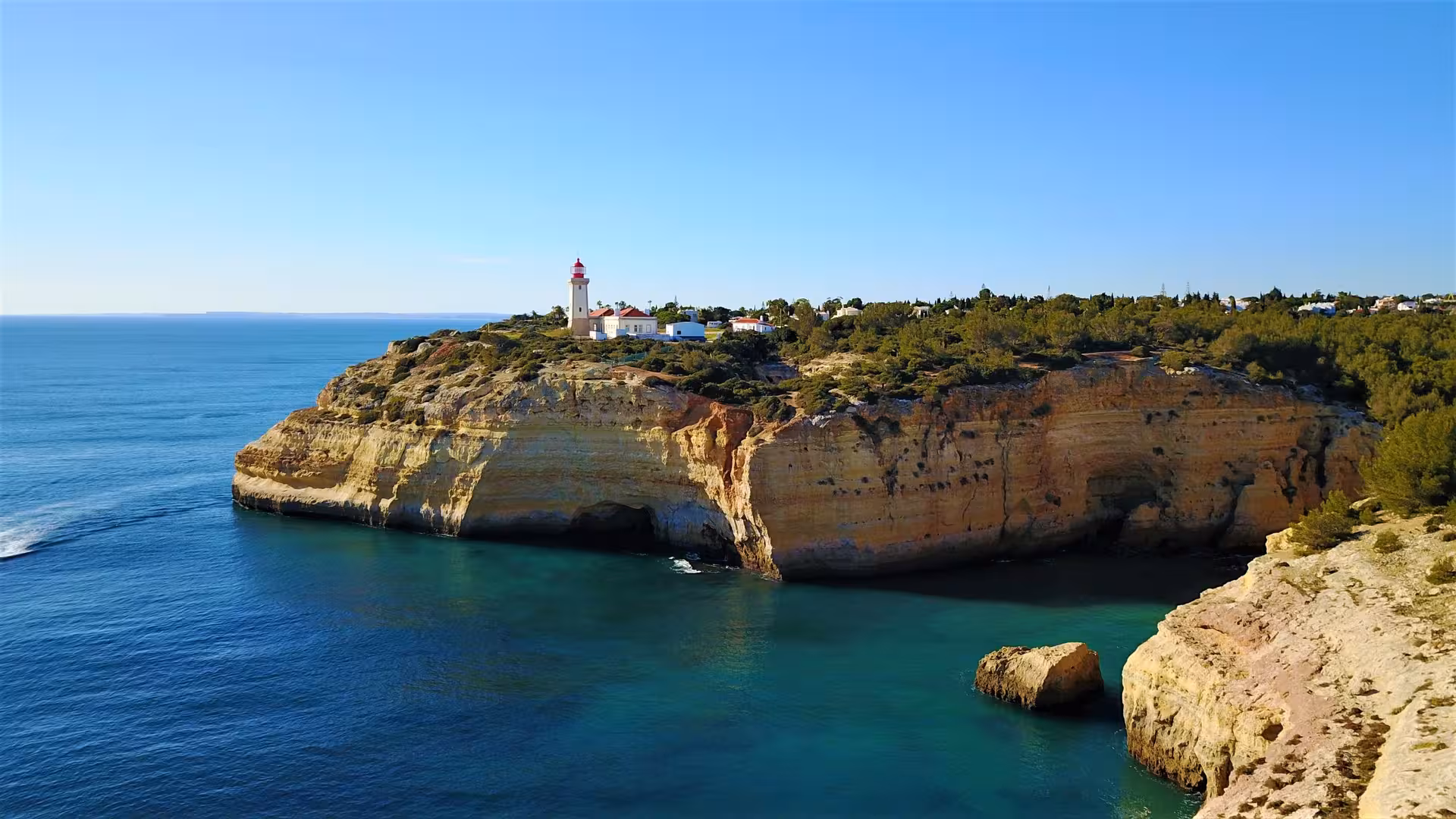 Discover the picturesque coastal cliffs and lighthouse on the Dolphins and Caves tour, ideal for scenic photography.