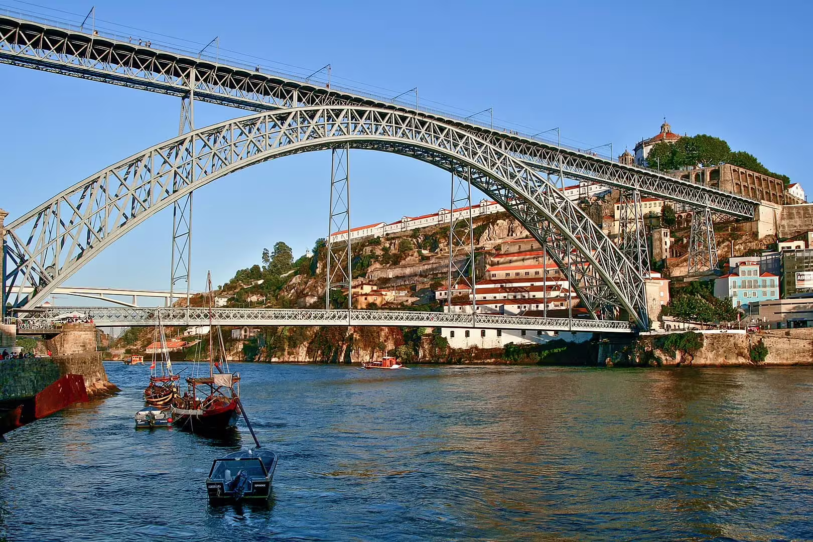 View of the iconic Dom Luís I Bridge connecting Porto and Gaia over the Douro River, highlighting scenic riverside architecture.