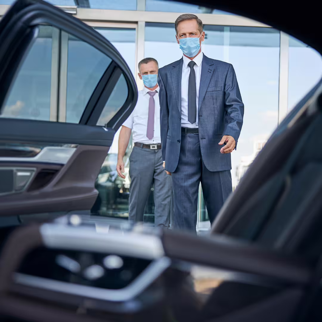 Business travelers wearing masks step into a luxury sedan for a private Domina Zagarella to Palermo airport transfer