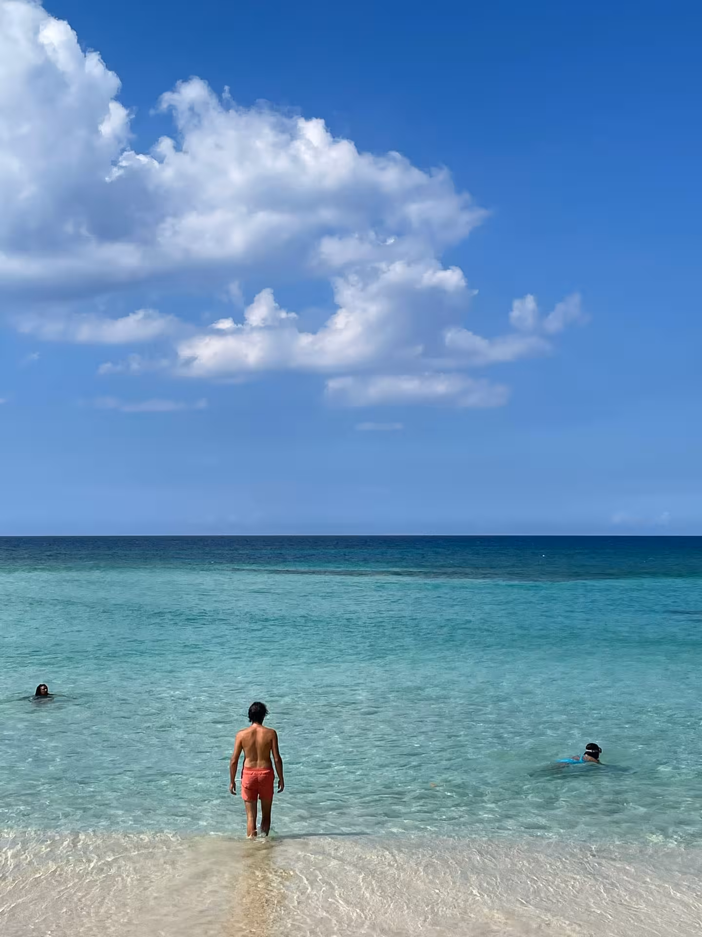 Traveler wading into crystal-clear Dominican Republic sea, mindful beach moment on a 7-day wellness journey