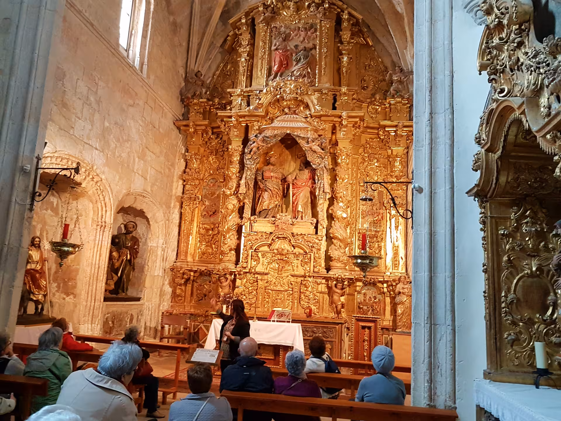 Guided visit inside a La Mancha church with ornate golden altarpiece, cultural stop on Don Quixote Tour