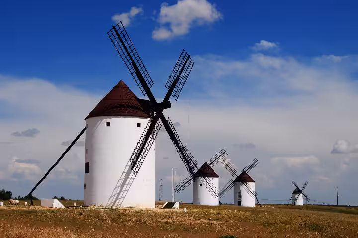 Iconic white windmills of La Mancha under blue sky, classic Don Quixote tour photo spot in Spain