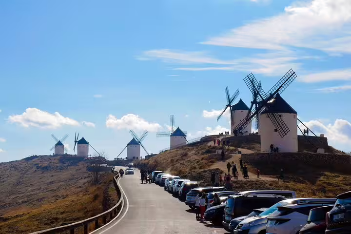A scenic view of the La Mancha windmills lined along a hilltop road, part of the Don Quixote and Toledo tour experience.