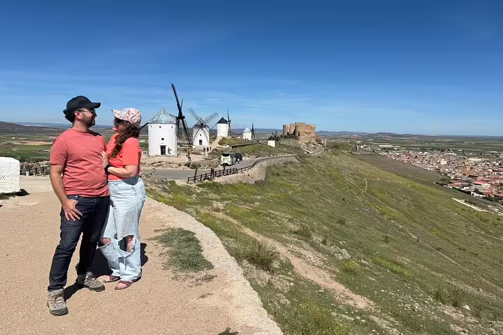 Couple enjoys scenic view of Don Quixote windmills in La Mancha during guided tour with Toledo lunch option.