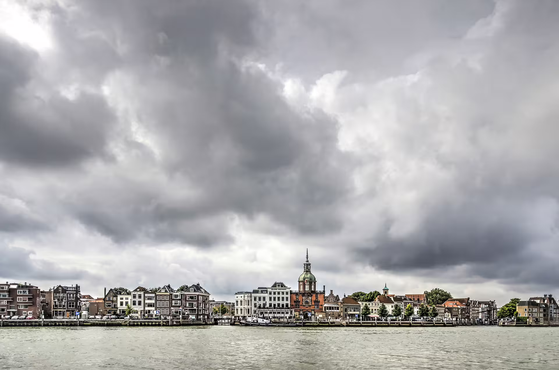 Dordrecht riverfront panorama with historic center and town hall under dramatic clouds, 1-day audioguide walk