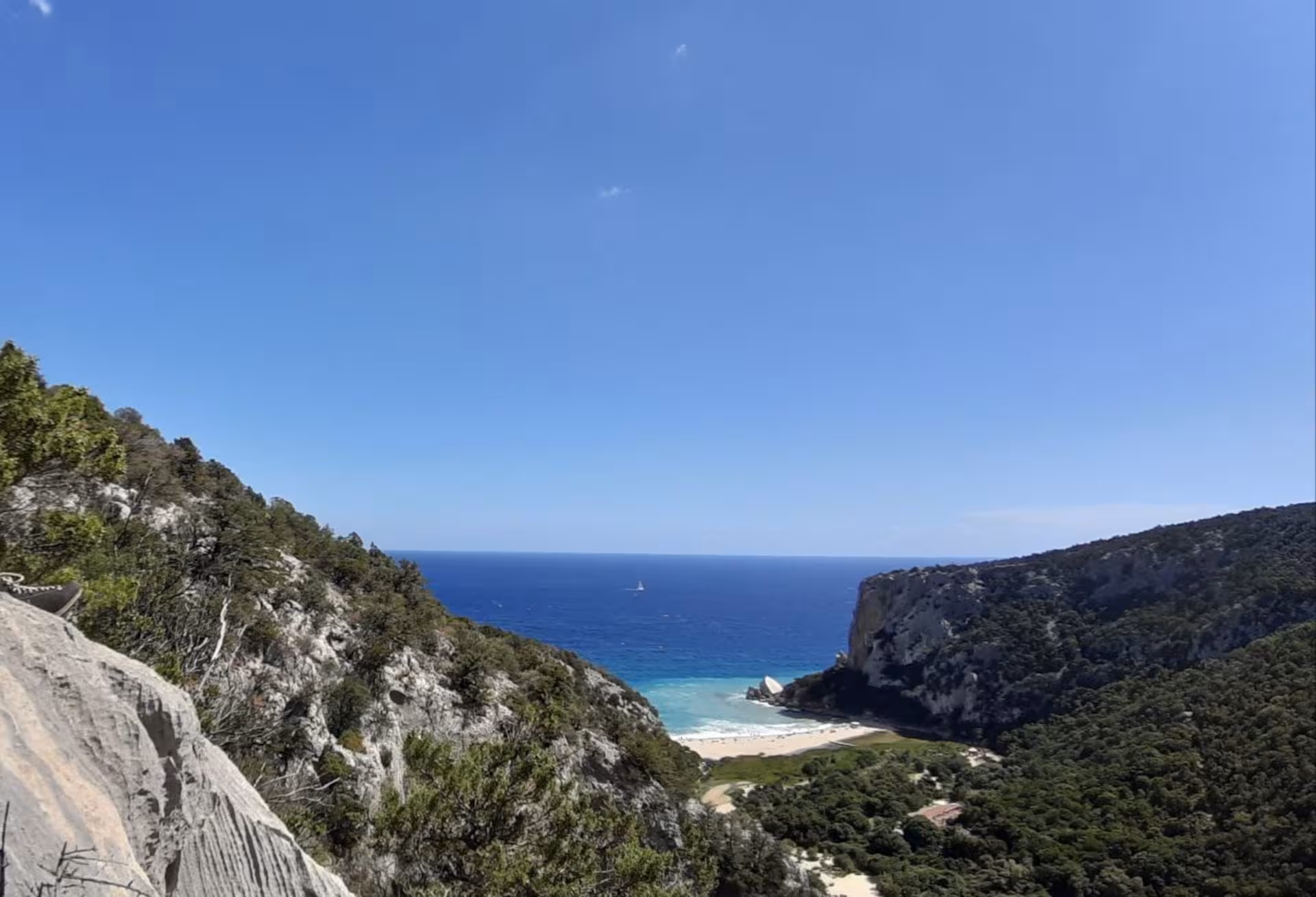 Breathtaking view of Cala Luna's turquoise waters and cliffs from a high vantage point on the trek.