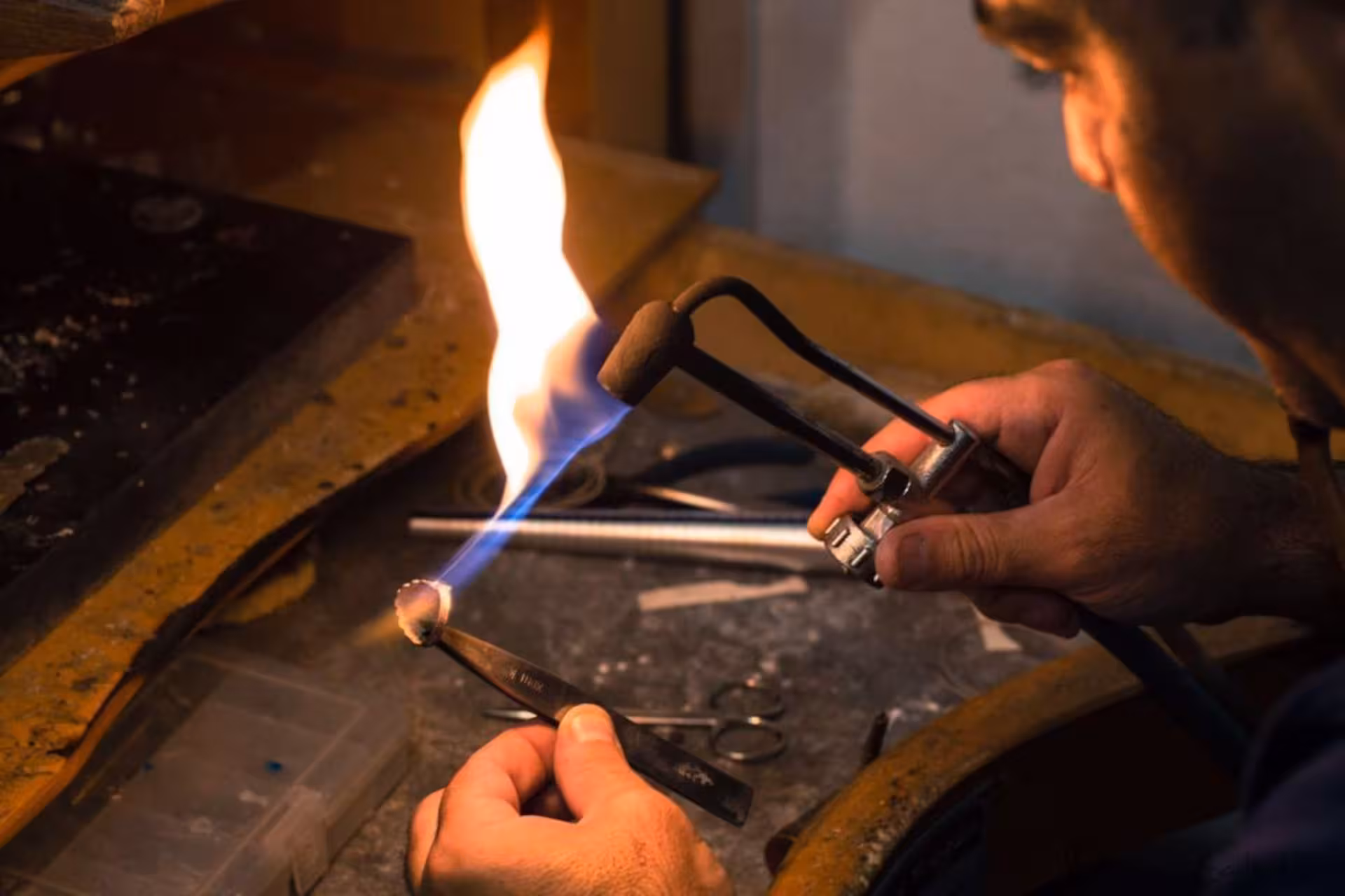 Craftsman in Dorgali goldsmith lab using torch to create intricate Sardinian filigree jewelry.