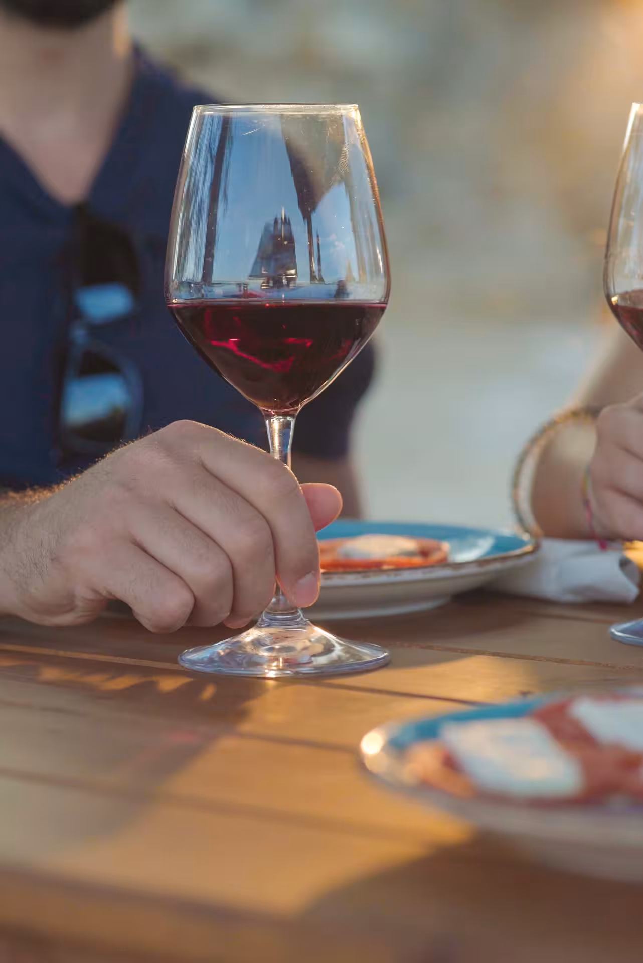Close-up of a person holding a glass of red wine during a tasting session at a Dorgali winery.