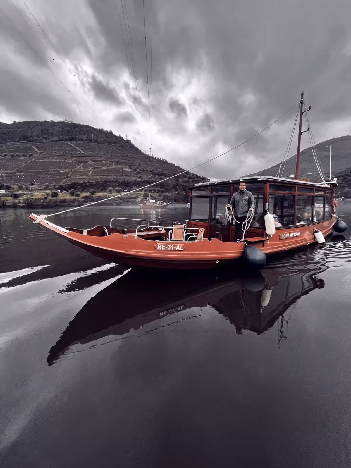 Traditional Douro River boat cruise with terraced vineyards and dramatic skies on a panoramic tour
