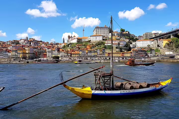 Traditional boat floats on Douro River with colorful Porto skyline in the background, perfect for a full-day private tuk-tuk tour.