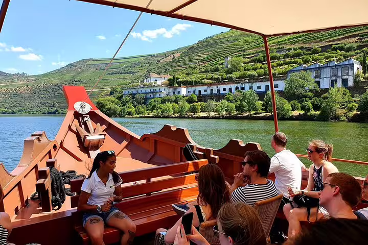 Tourists enjoy a scenic Douro River cruise with views of lush vineyards and historic estates in Porto's wine country.