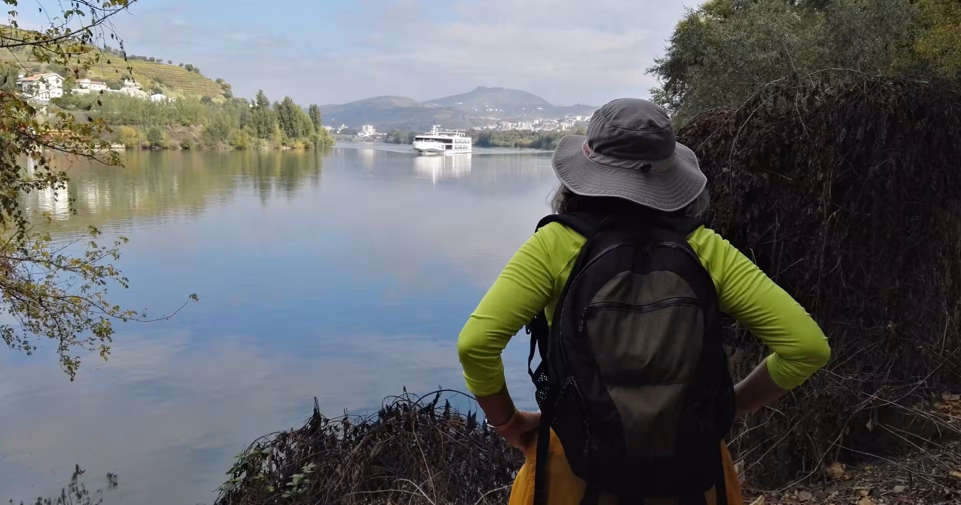 Hiker overlooking the Douro River with cruise boat, a scenic stop on the 7-day Lisbon to Porto tour