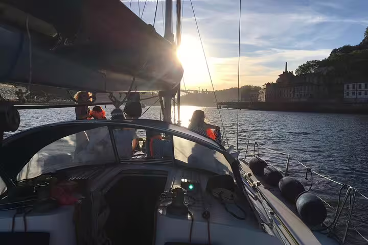 Sailboat gliding on the Douro River at sunset in Porto, offering a serene and picturesque sailing experience.