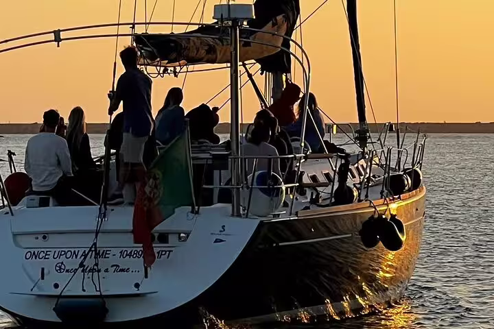 Sailboat gliding on Douro River at sunset with passengers enjoying a scenic Porto view, perfect for a relaxing evening cruise.